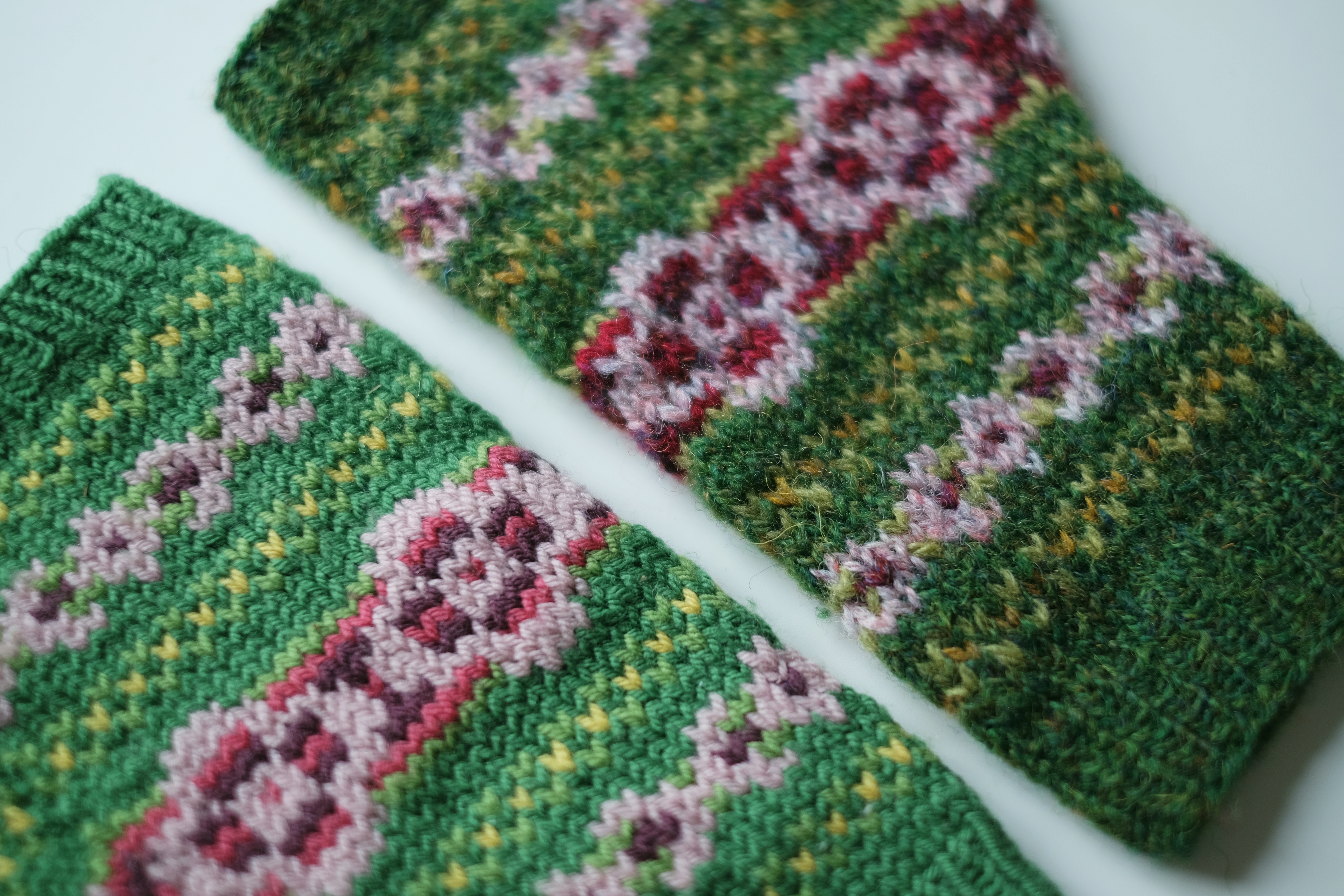 A closeup of two of the mitts showing the difference in yarn texture and color composition. The more rustic texture and heathered colors of the Shetland yarn are very visible.