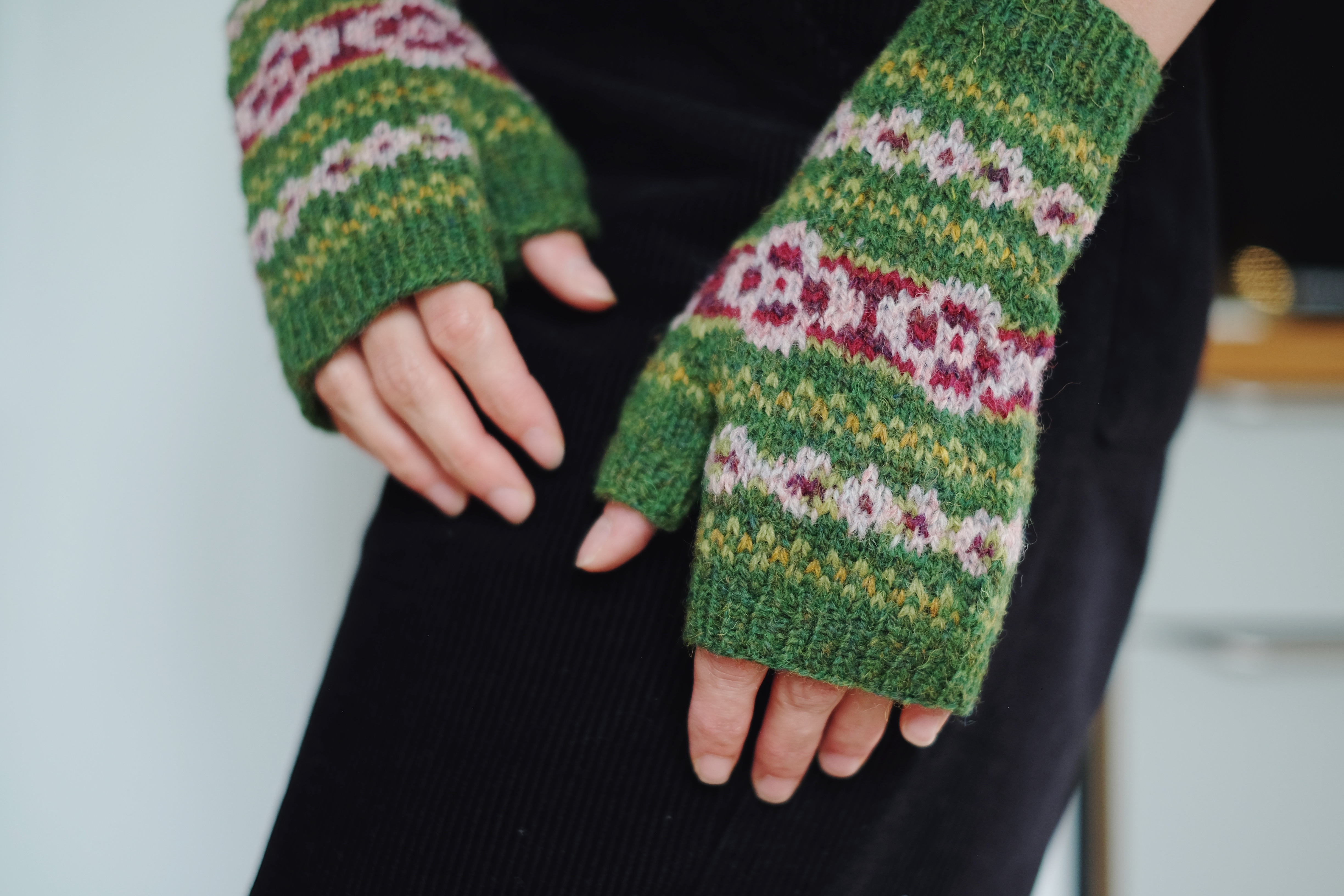 A pair of green fair isle mitts in heathered shades are