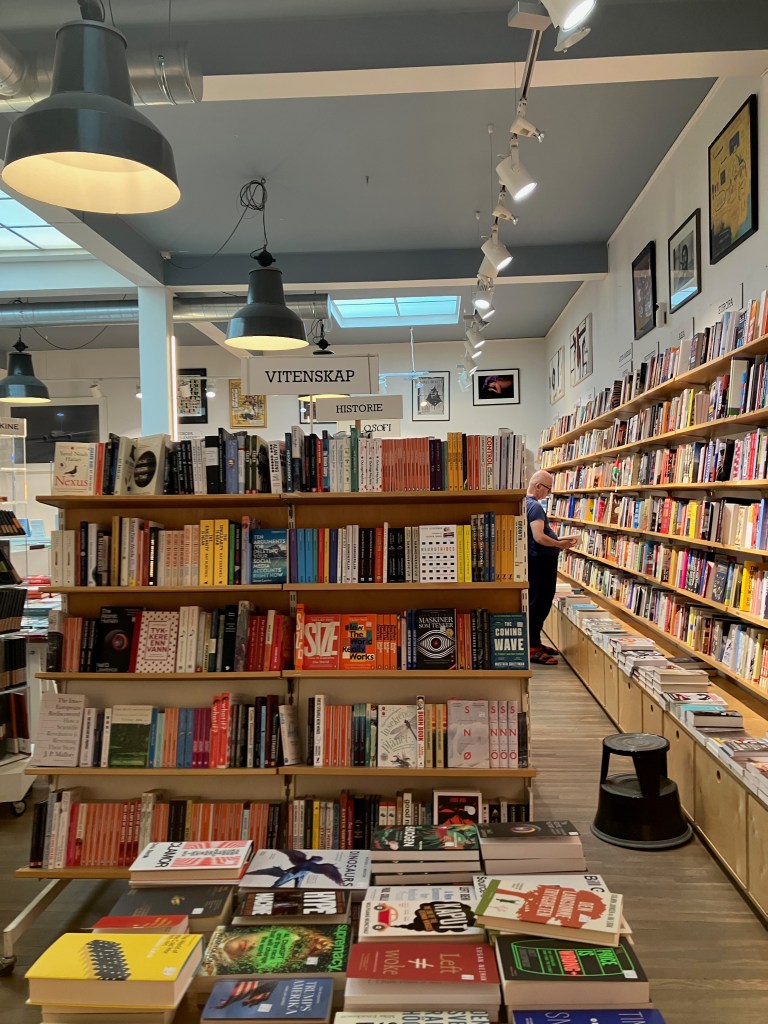 A bright bookstore space with shelves along the walls and in the middle of the room, and high windows in the wall.