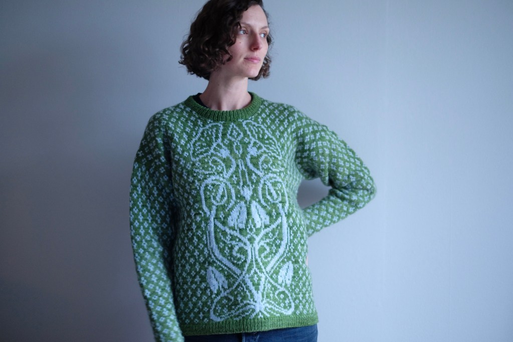 Dianna wears the sweater, looking to one side towards the light with one hand on her hip.