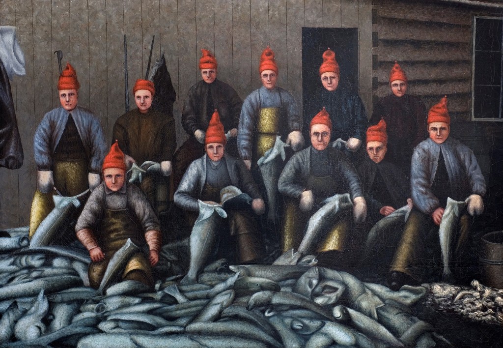 A painting of eleven fishermen gutting cod. All are facing the viewer and all are wearing pointed red knitted hats.